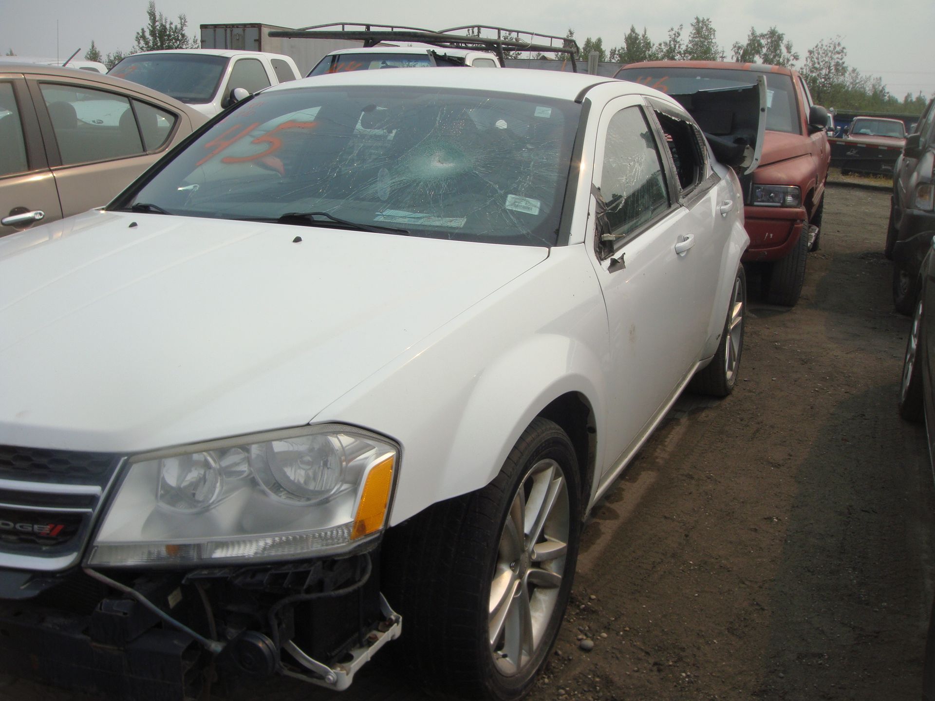 A white car is parked in a lot with other cars