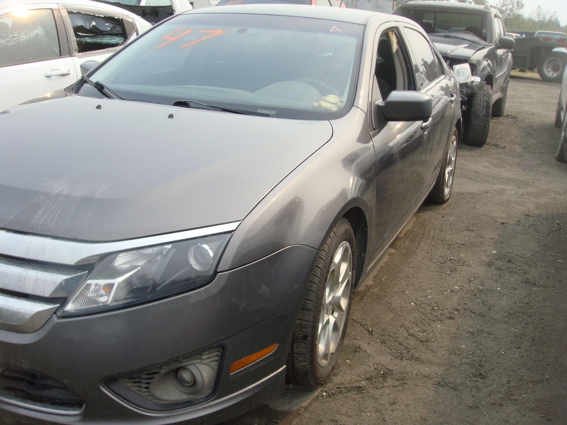 A gray car is parked in a lot with other cars.