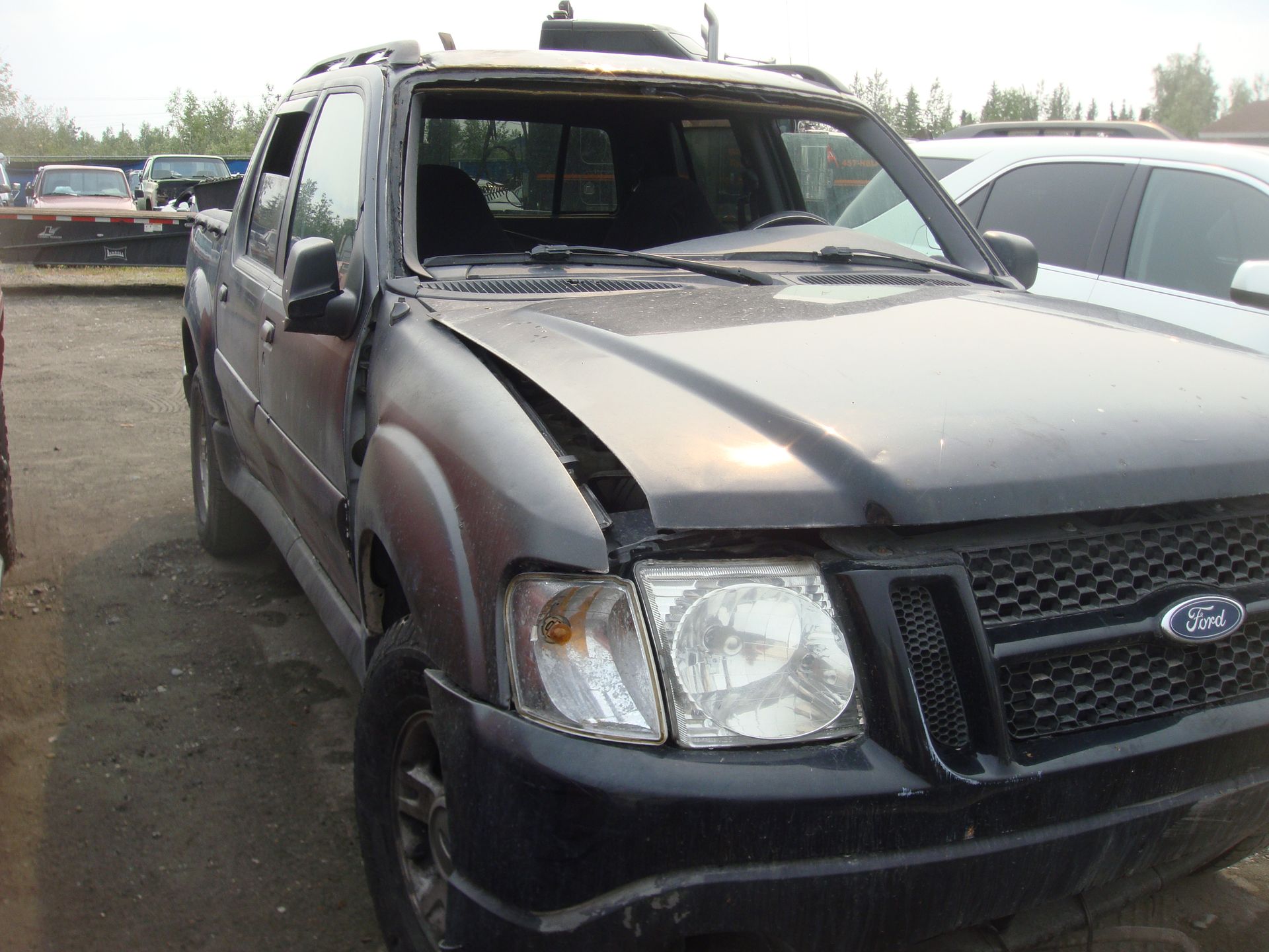 A black ford truck with a broken windshield is parked in a lot