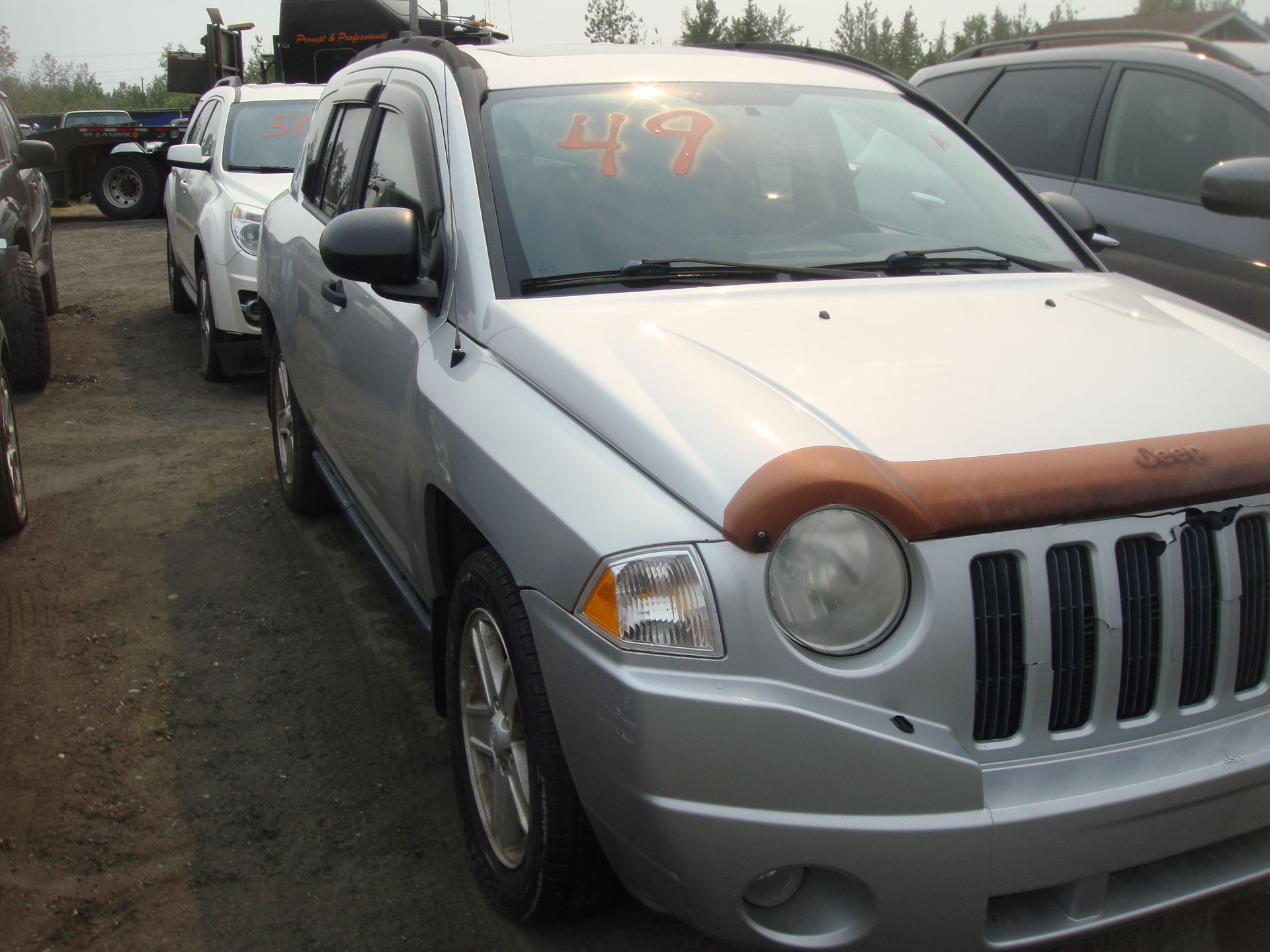 A silver jeep compass is parked in a lot