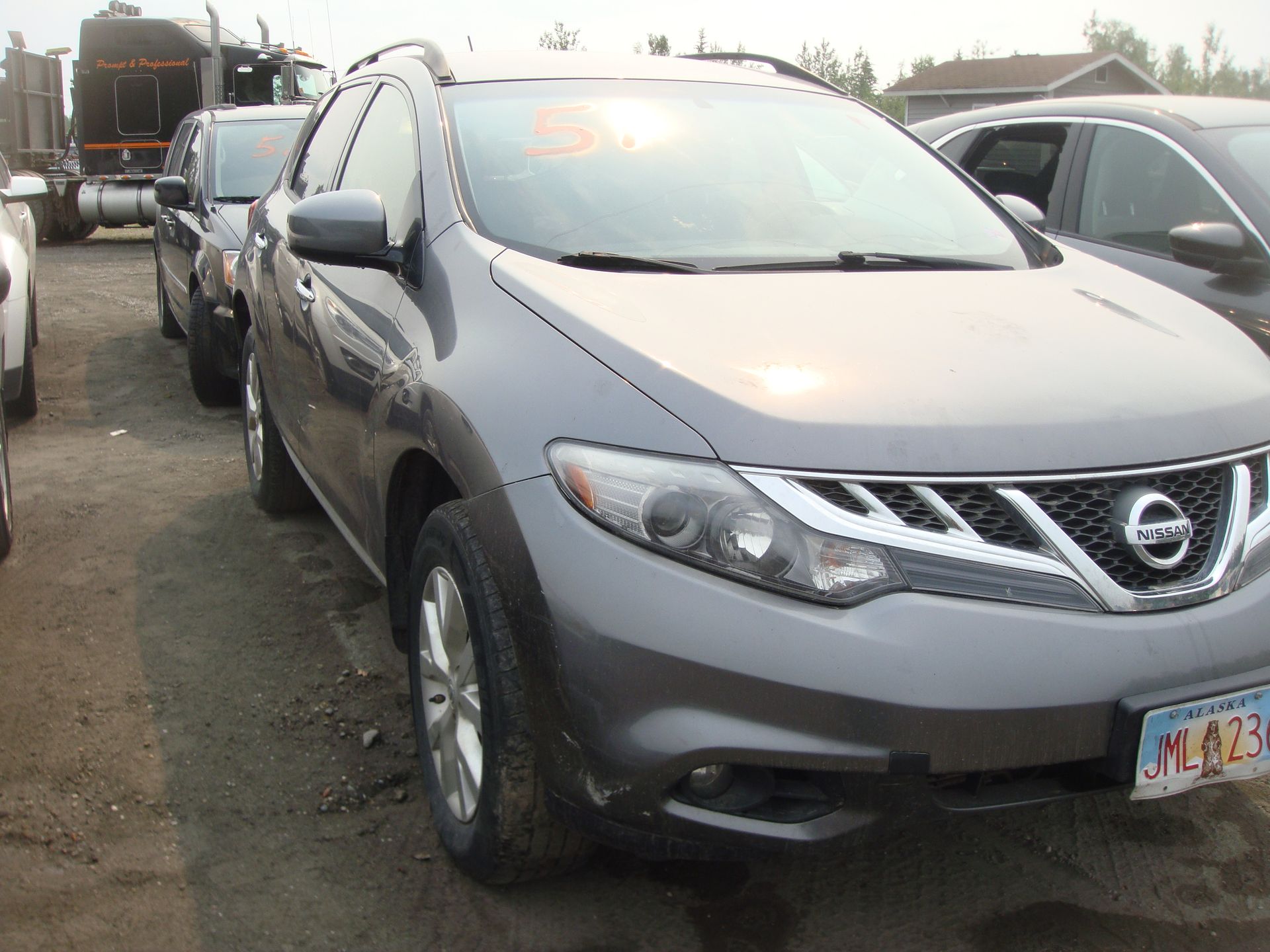 A gray nissan murano is parked in a parking lot