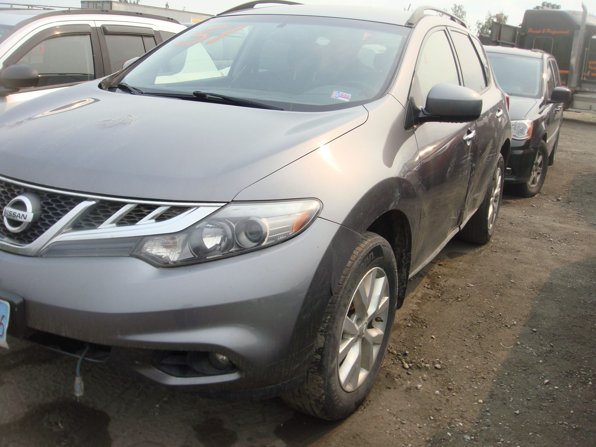 A gray nissan murano is parked in a parking lot.