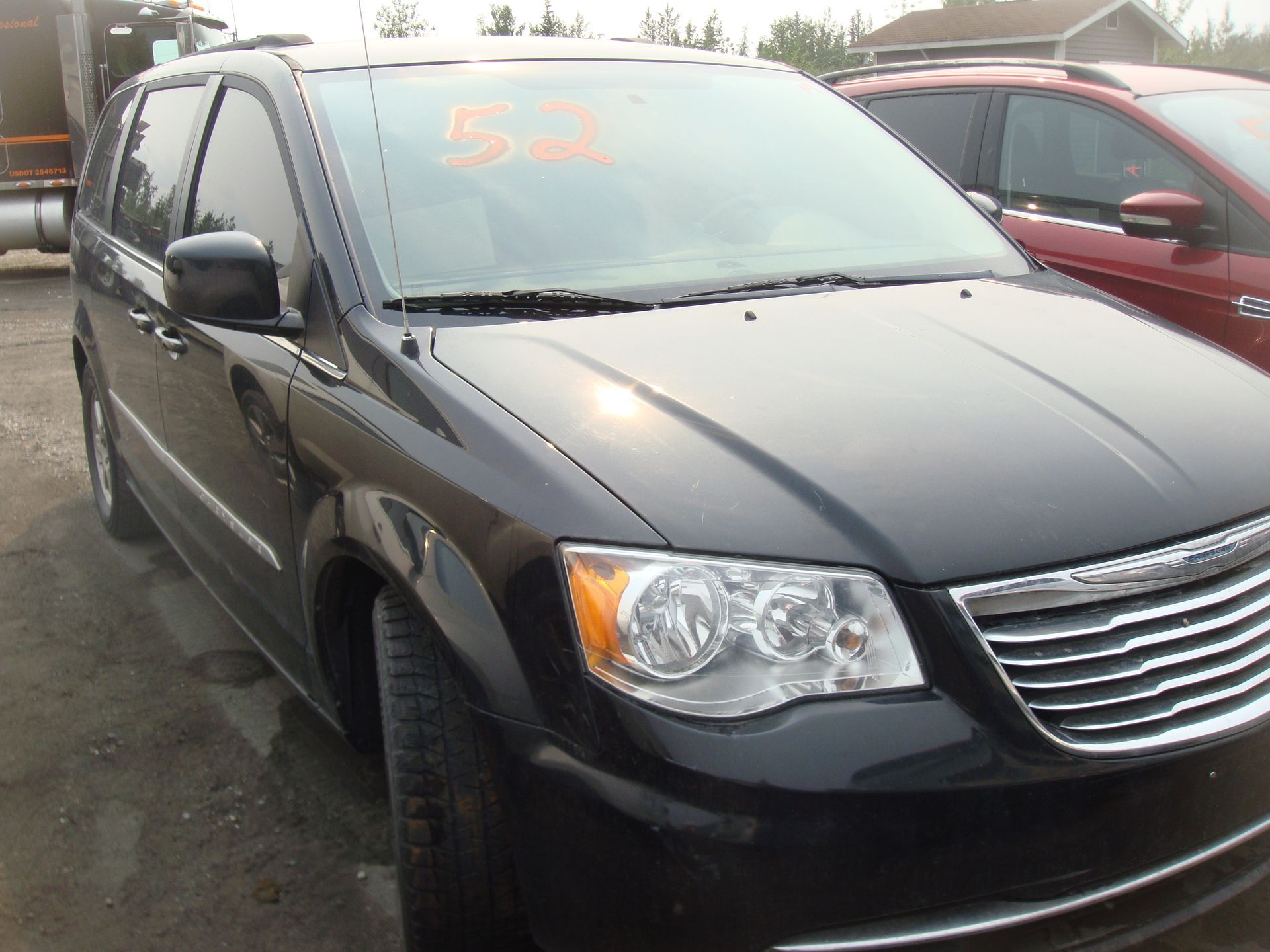 A black chrysler minivan is parked in a parking lot