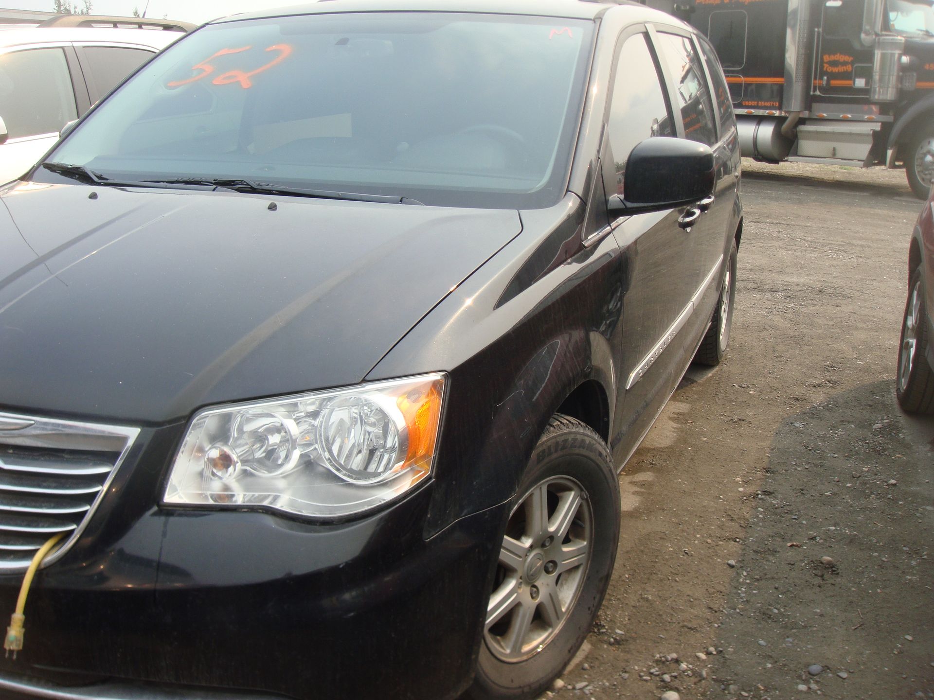 A black chrysler minivan is parked in a parking lot