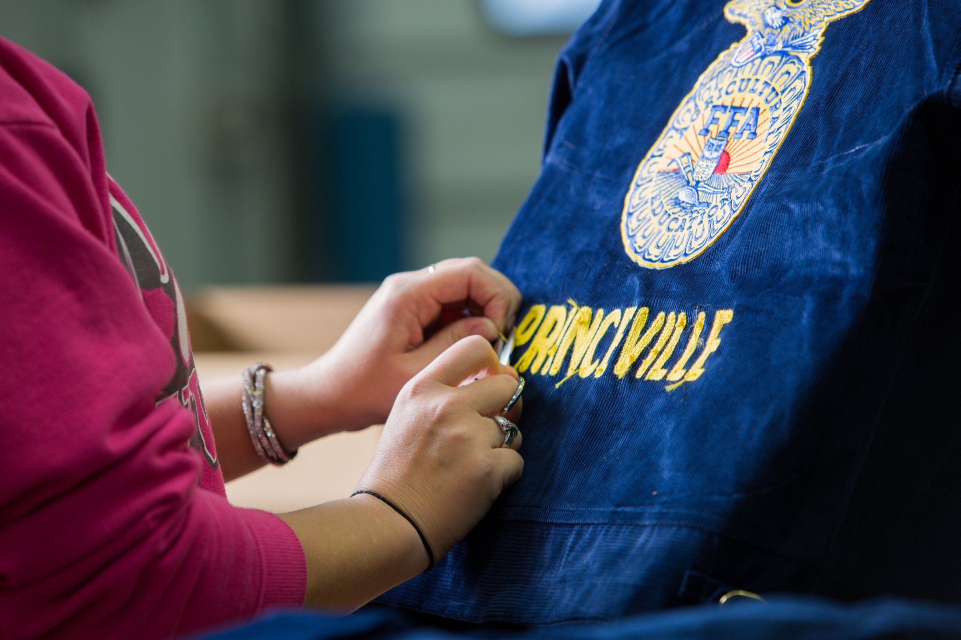 Person stitching a name on a FFA jacket 
