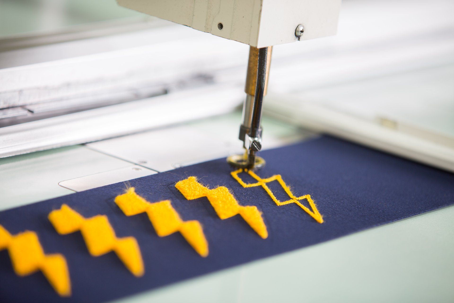 A lightning pattern being sewed onto blue fabric.