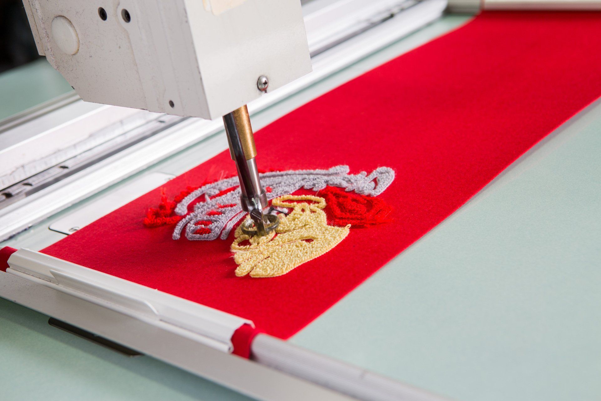 A custom Chenille patch partway through being sewed into red fabric.