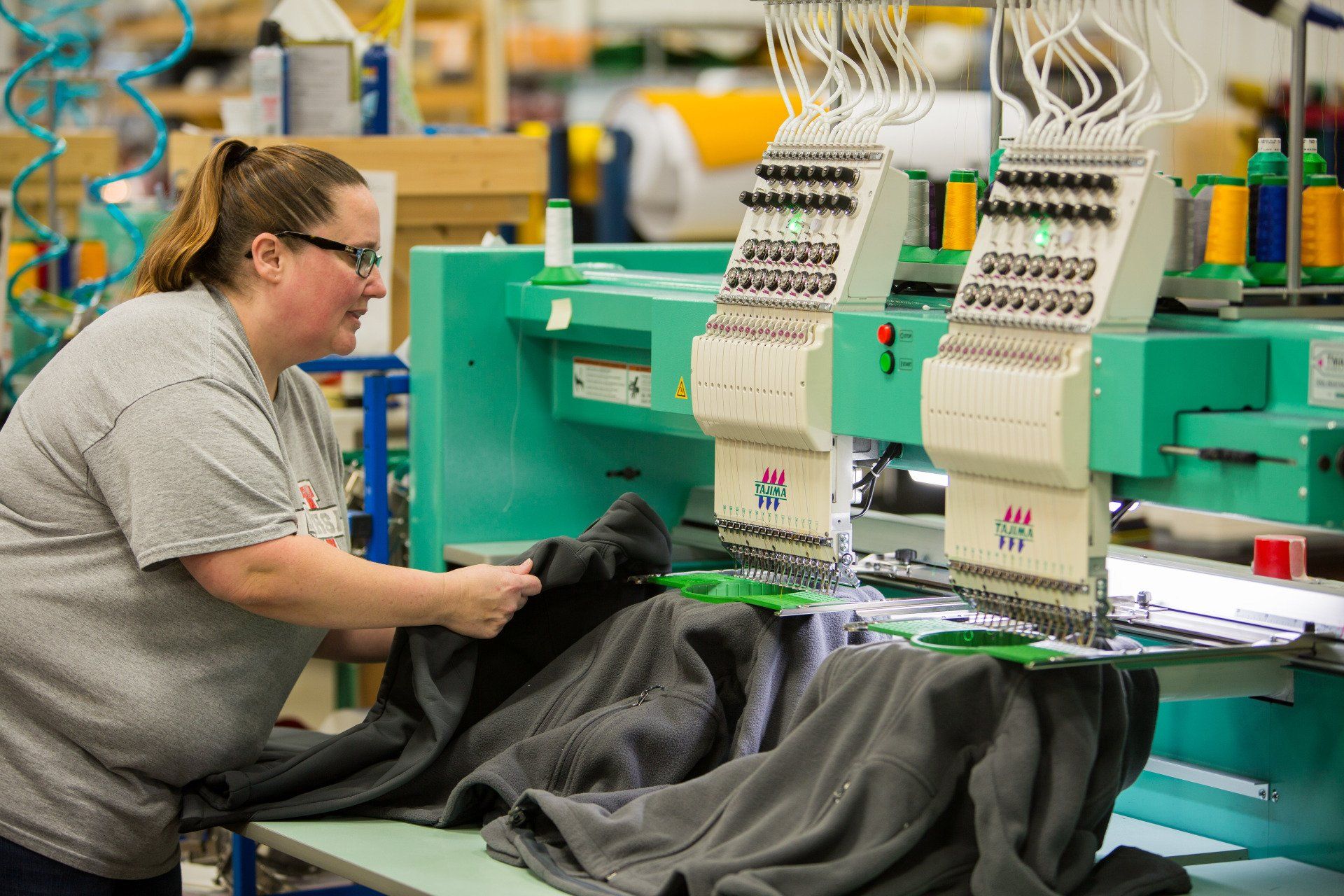 A woman sewing custom names onto a jacket.