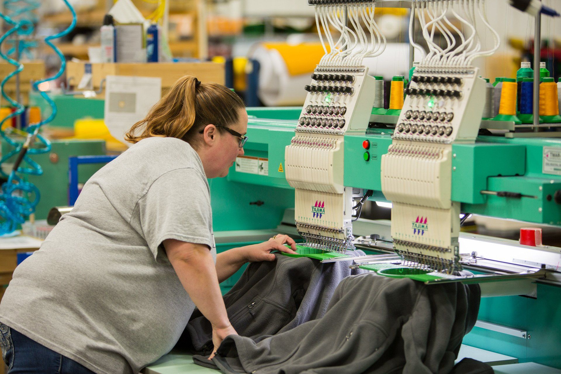 A woman sewing custom names onto a jacket.