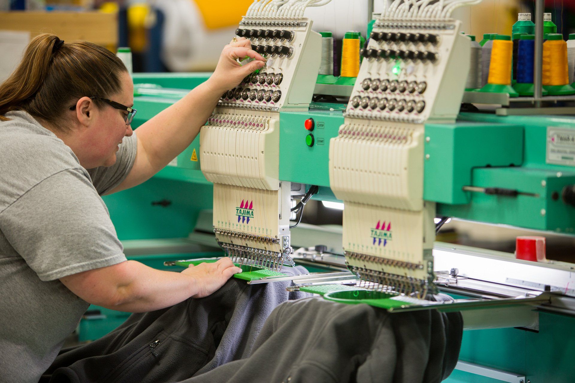 A woman sewing chenille patches on jackets.