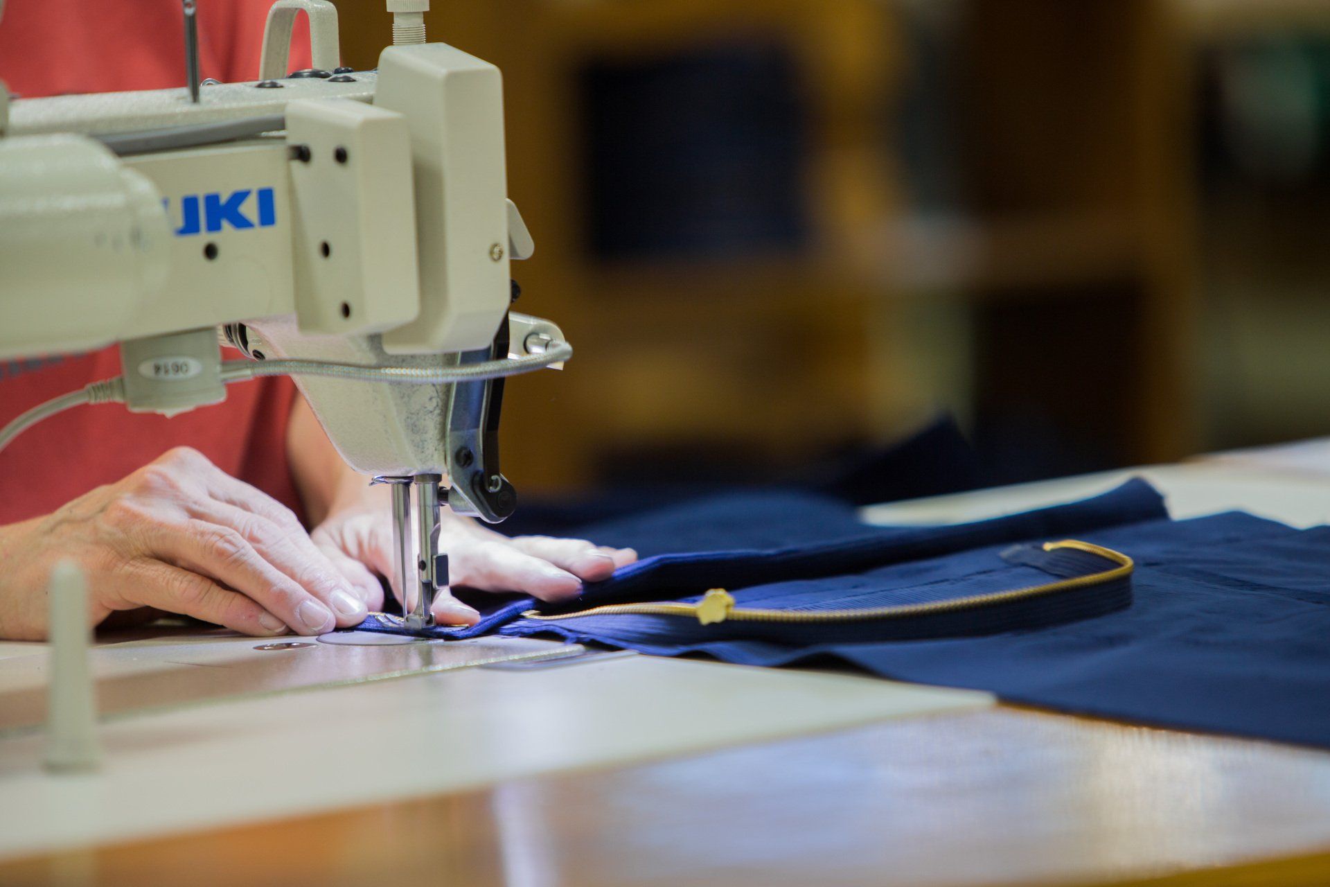 Person sewing a zipper on a FFA jacket.