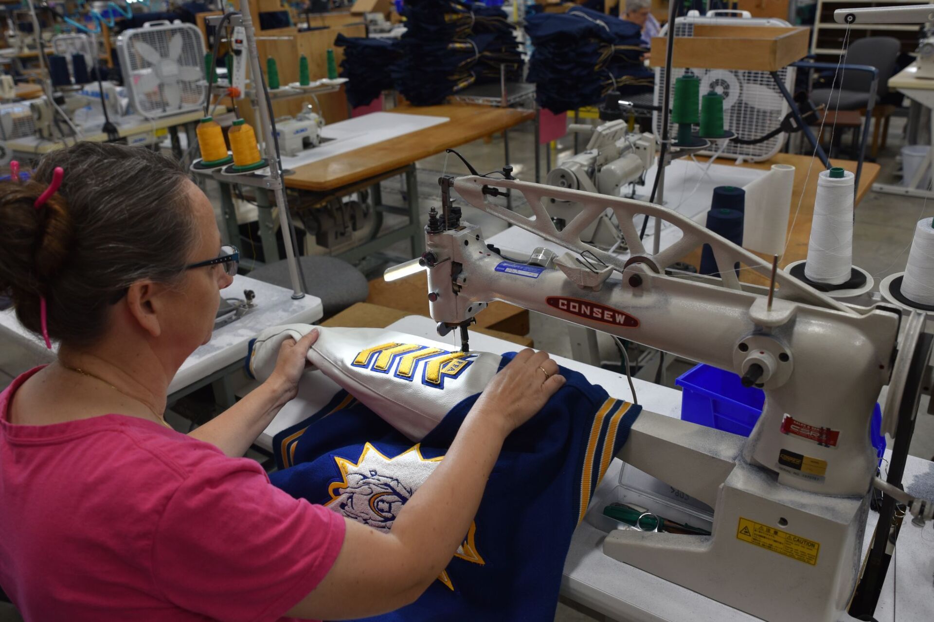 A woman sewing a pattern onto a FFA jacket.