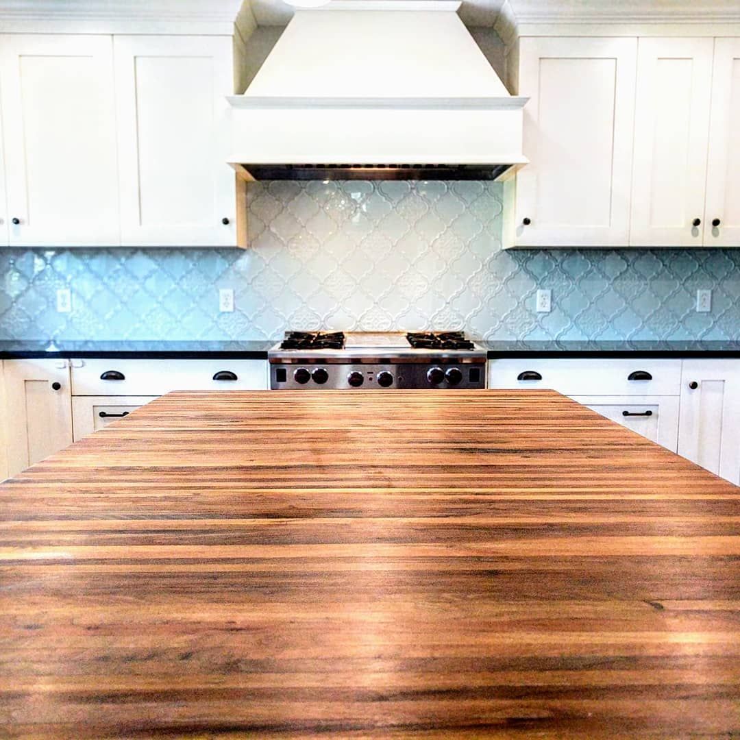 A kitchen with white cabinets and a wooden counter top.