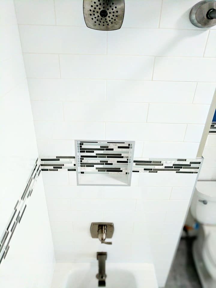 A bathroom with a shower , sink , toilet and shower head.