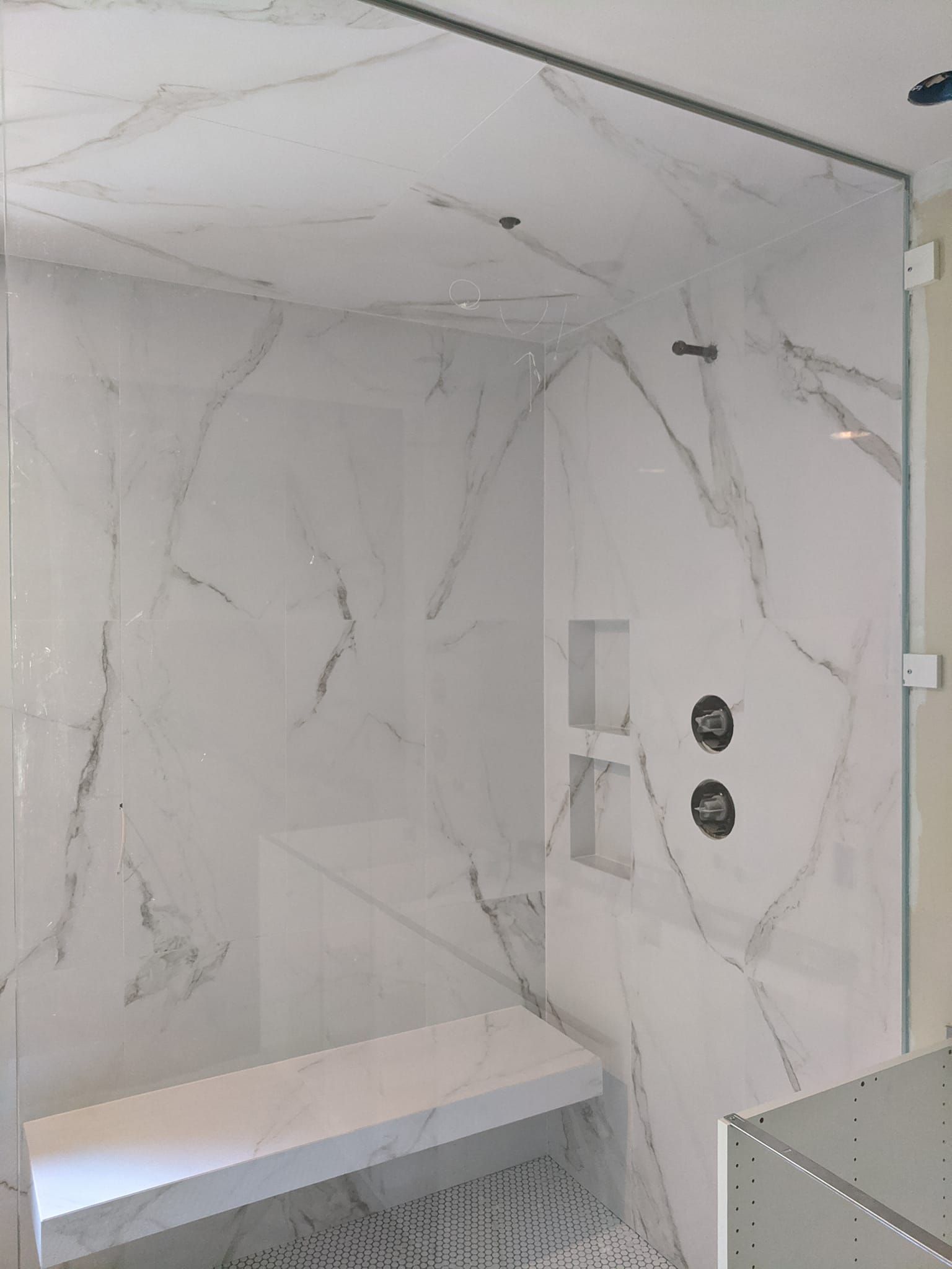A bathroom with a walk in shower and a bench.