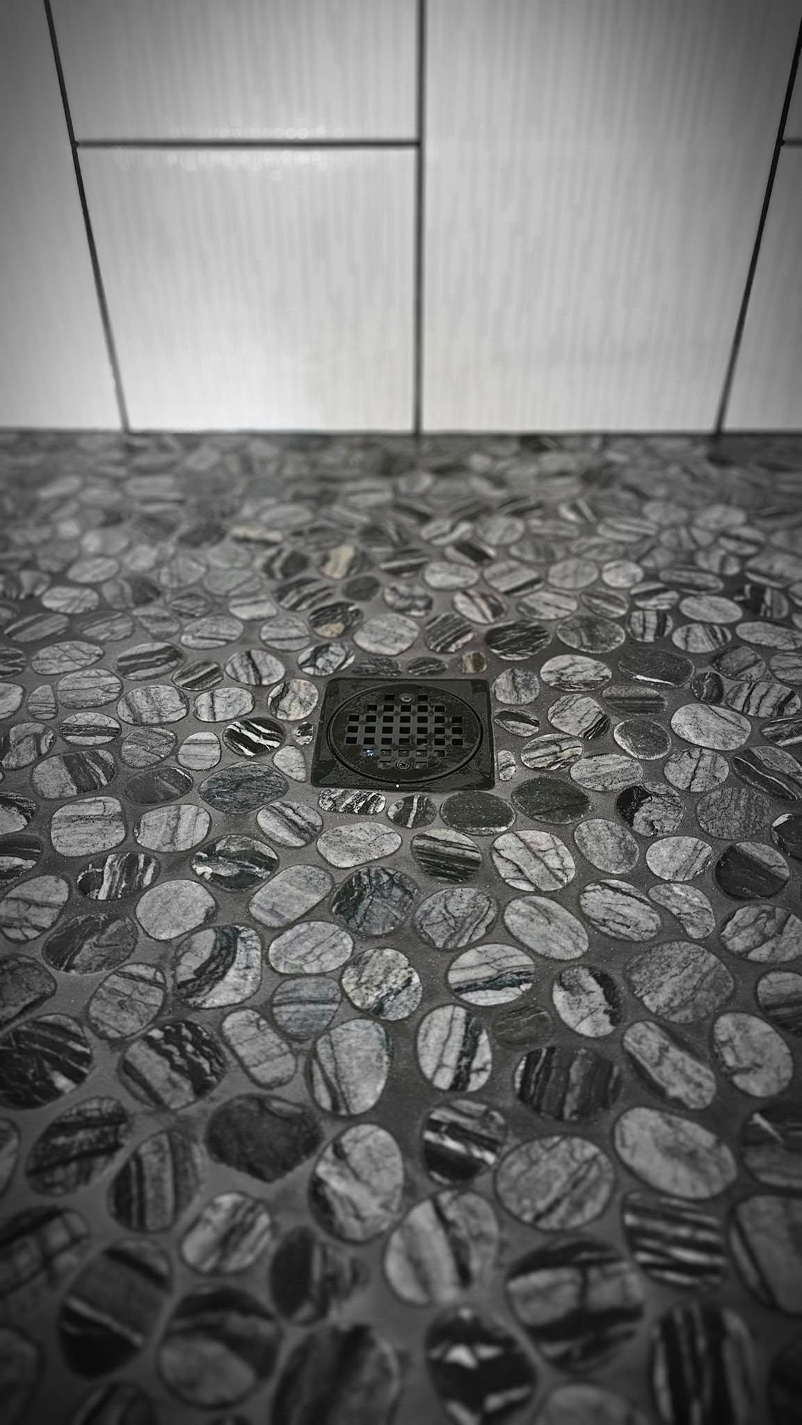 A black and white photo of a shower floor with a drain.