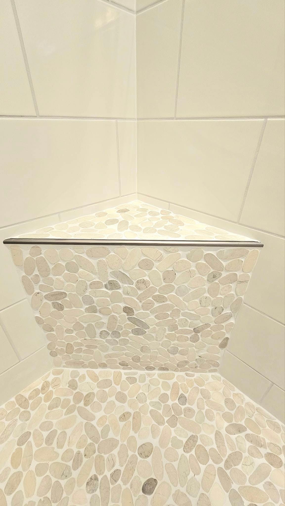 There is a corner shelf in the shower with marble tiles.