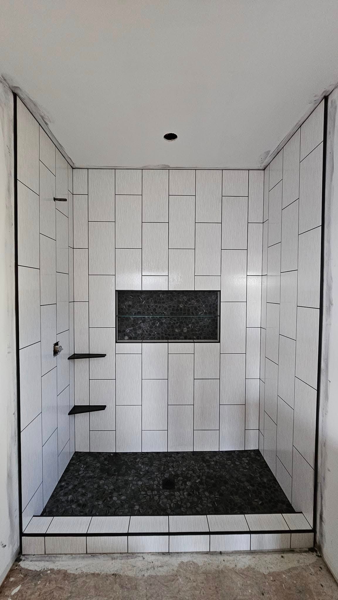A bathroom with white tiles and a black floor.