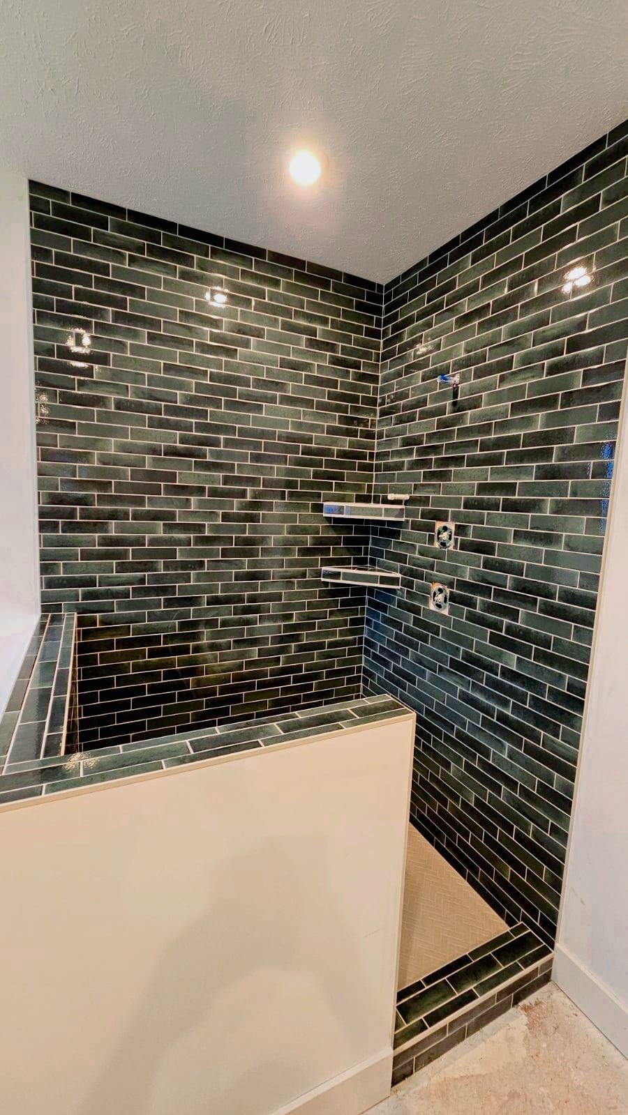 A bathroom with a walk in shower and a brick wall.