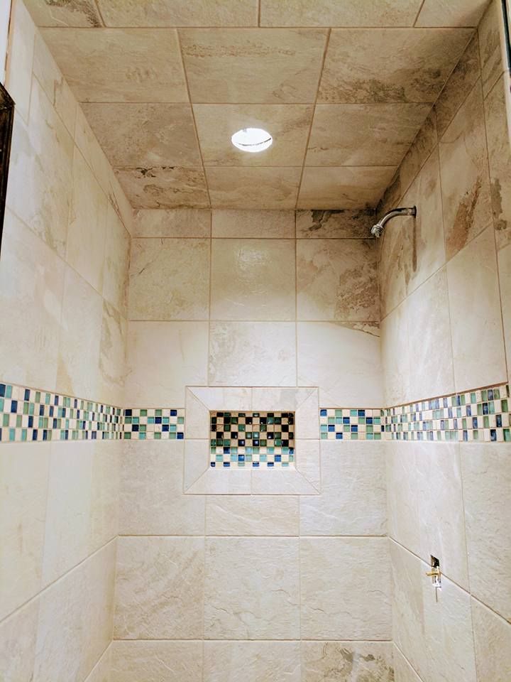 A bathroom with tiled walls and a shower head.