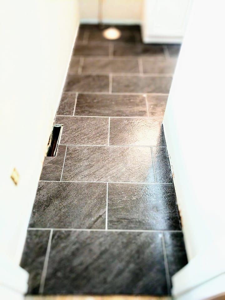 A narrow hallway with a tiled floor and a white wall.