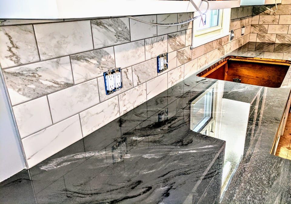 A kitchen with marble counter tops and a copper sink.