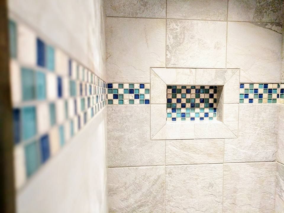 A close up of a shower with blue and white tiles on the wall.
