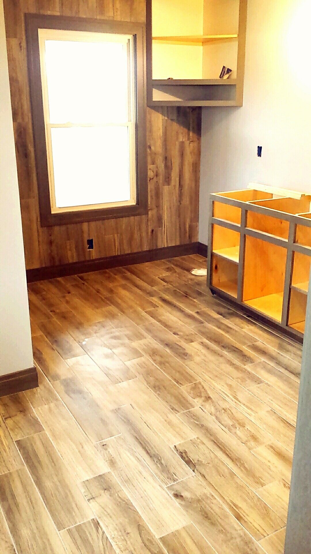 A room with wooden floors and cabinets and a window.