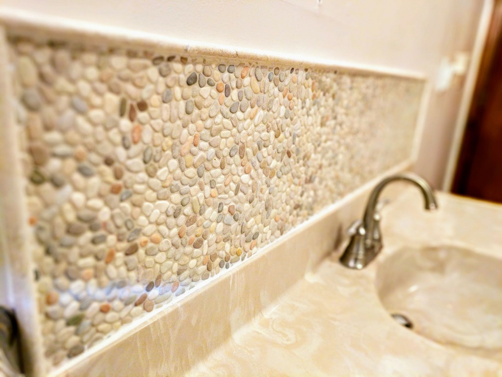 A bathroom sink with a stone wall behind it and a faucet.