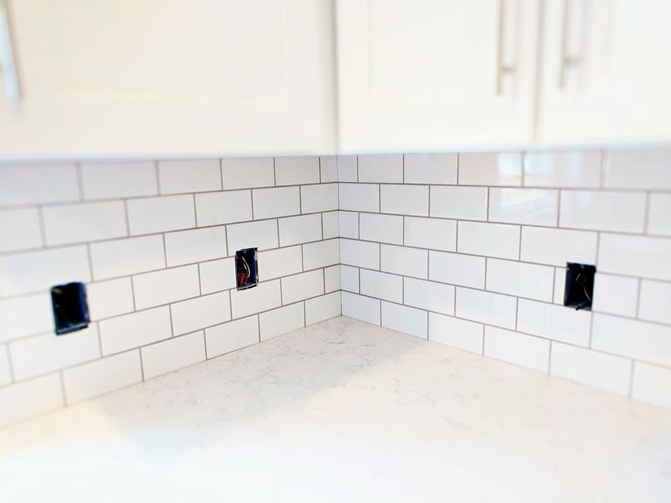 A kitchen with white subway tiles and black electrical outlets