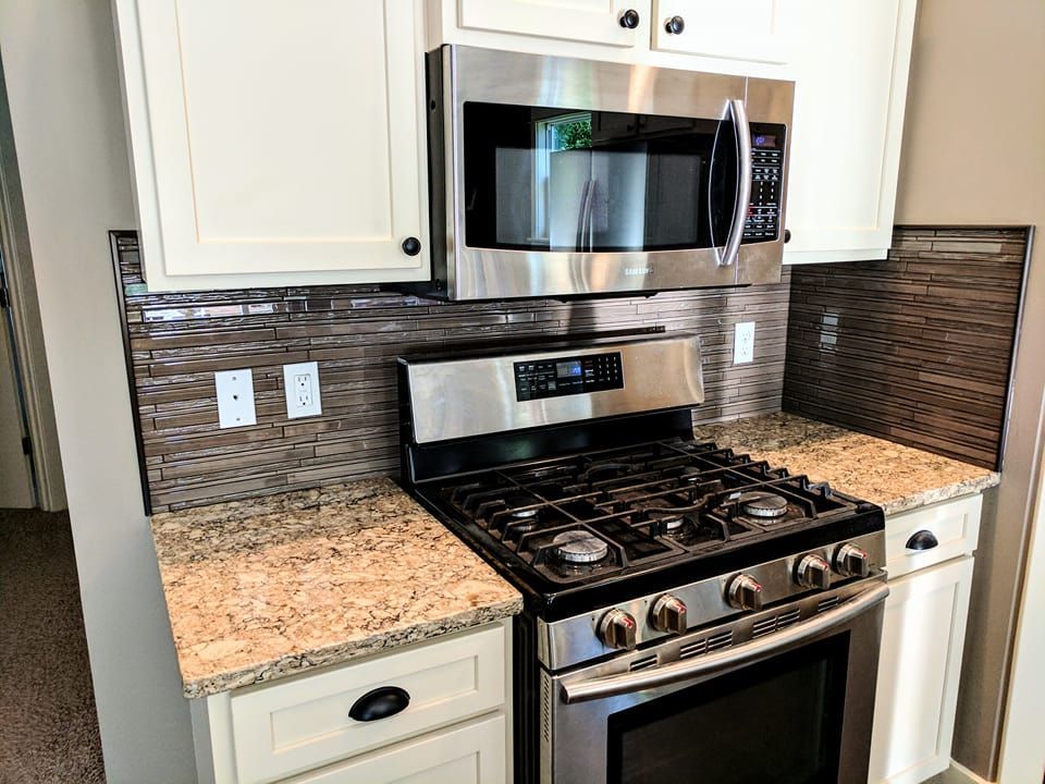 A kitchen with a stove , microwave , and granite counter tops.