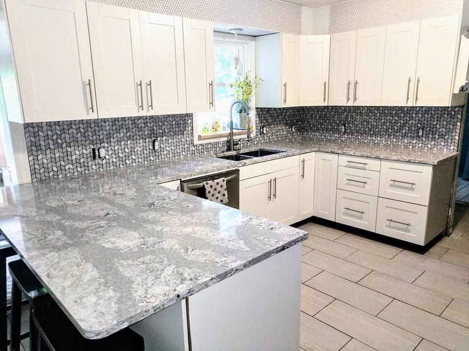 A kitchen with white cabinets and granite counter tops.