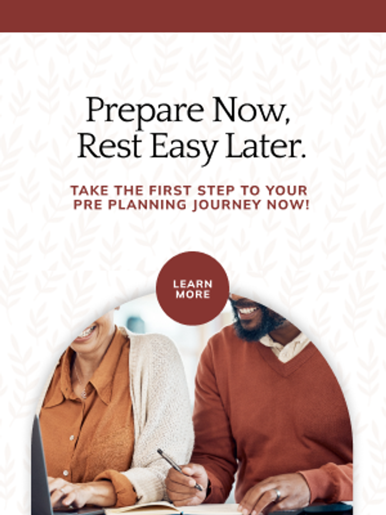 A couple sits together at a desk working on paperwork with a 