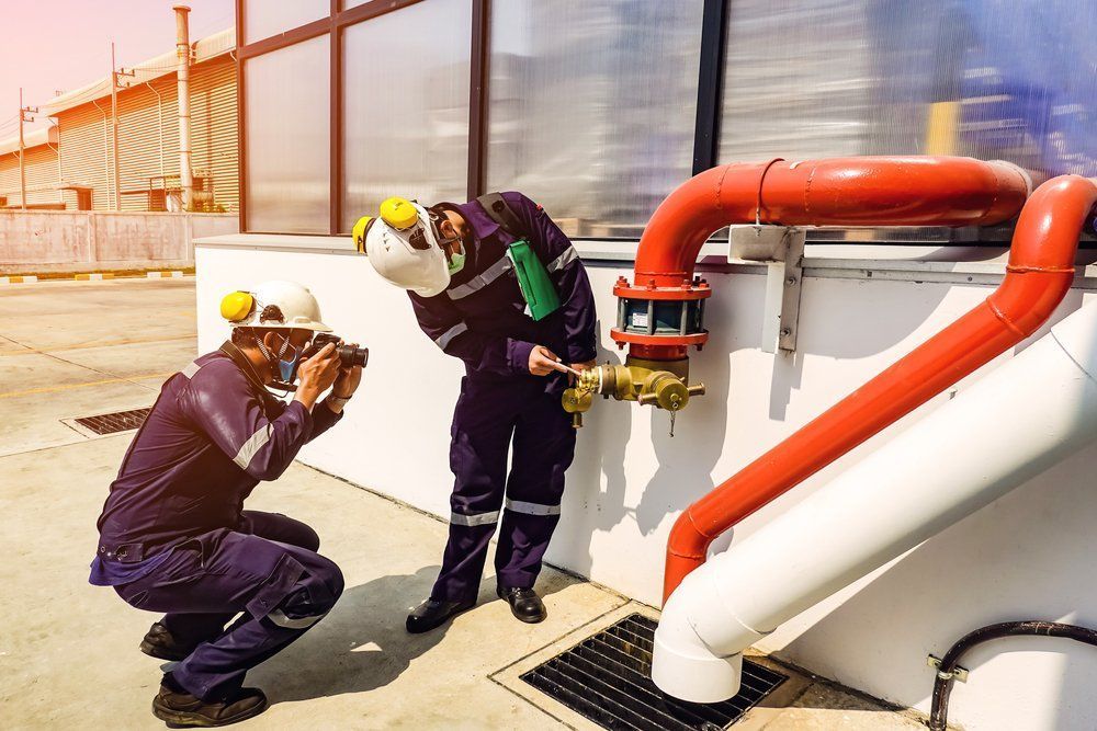 Two Workers Inspecting A Red Pipe — Wendy's Safety Services in Moulden, NT