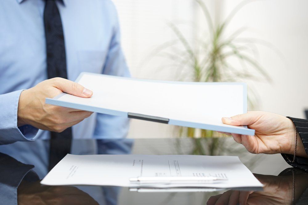 Person Handing A Document On A Clipboard To Another Person — Wendy's Safety Services in Moulden, NT