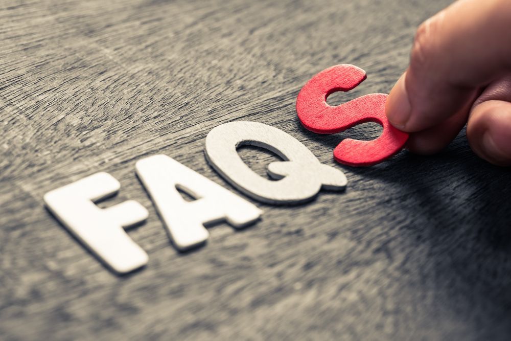 Hand Placing A Red “S” Next To “FAQ” Letters On A Wooden Surface — Wendy's Safety Services in Tennant Creek, NT