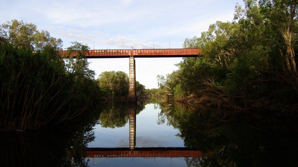 A Rusty Metal Bridge Spans A Calm River — Wendy's Safety Services in Katherine, NT