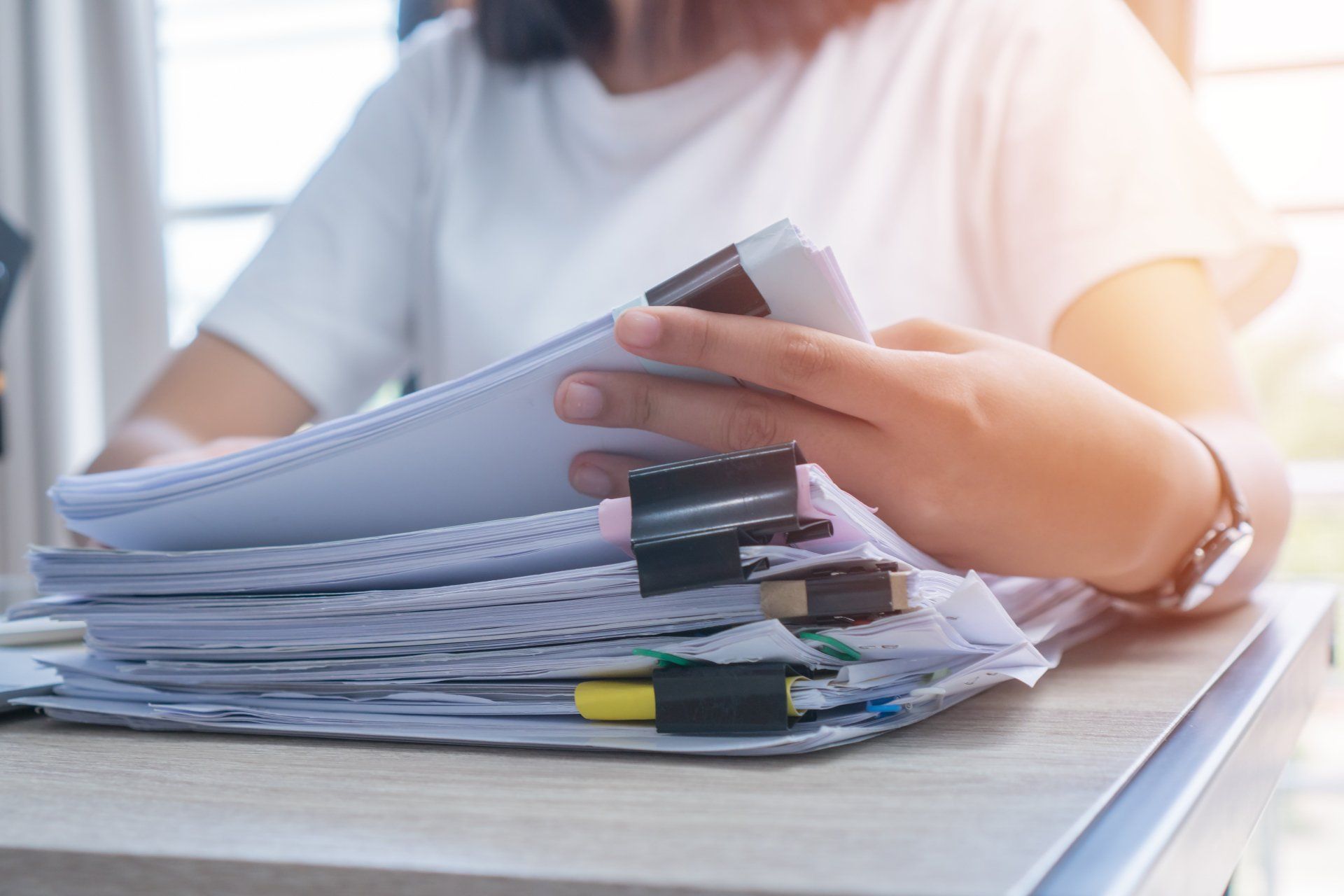 Person Organizing A Stack Of Papers Held Together With Binder Clips — Wendy's Safety Services in Moulden, NT