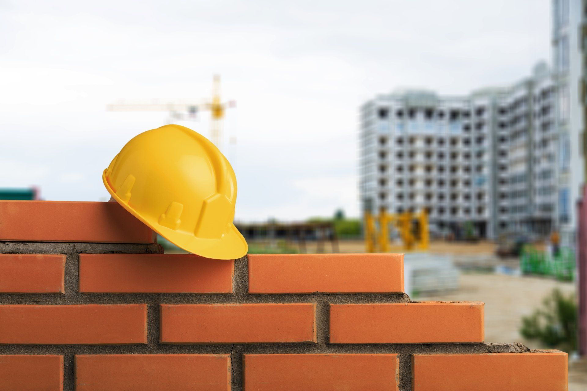 Yellow Hard Hat Resting On A Brick Wall At A Construction Site — Wendy's Safety Services in Moulden, NT
