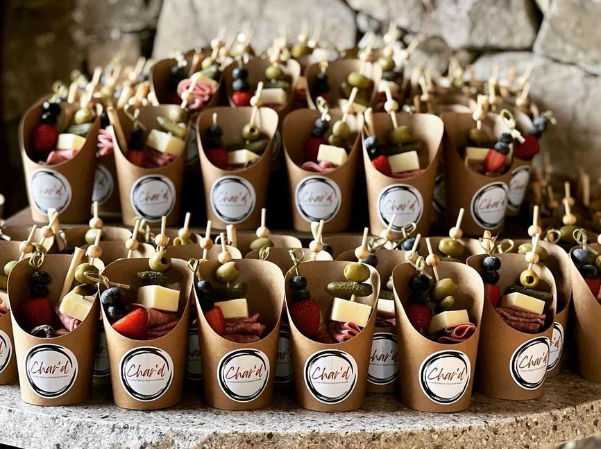 A table topped with paper cups filled with food on skewers.