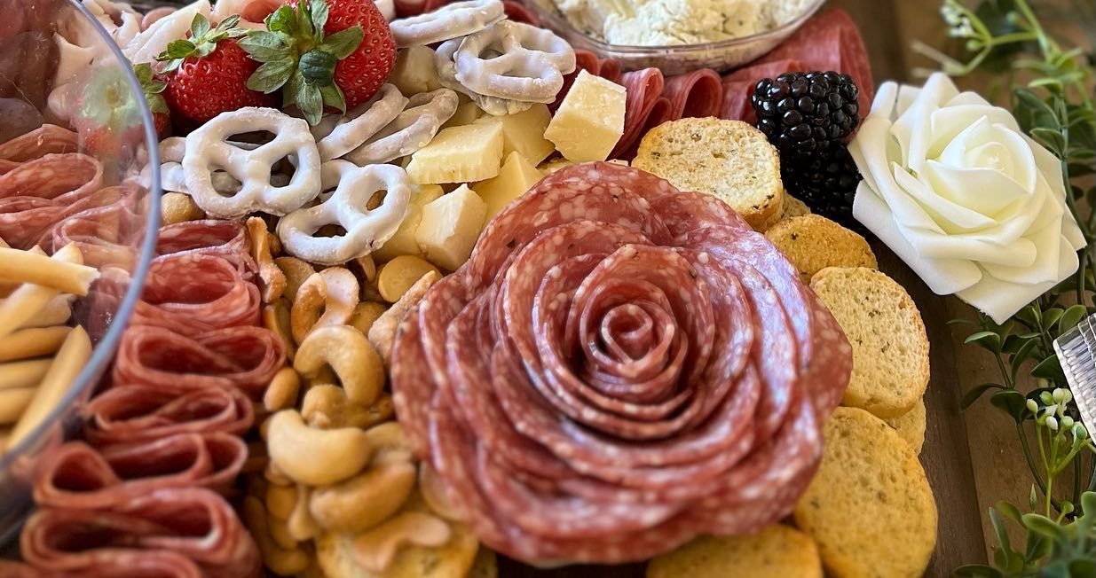 A tray of food with a rose shaped salami on top of it.