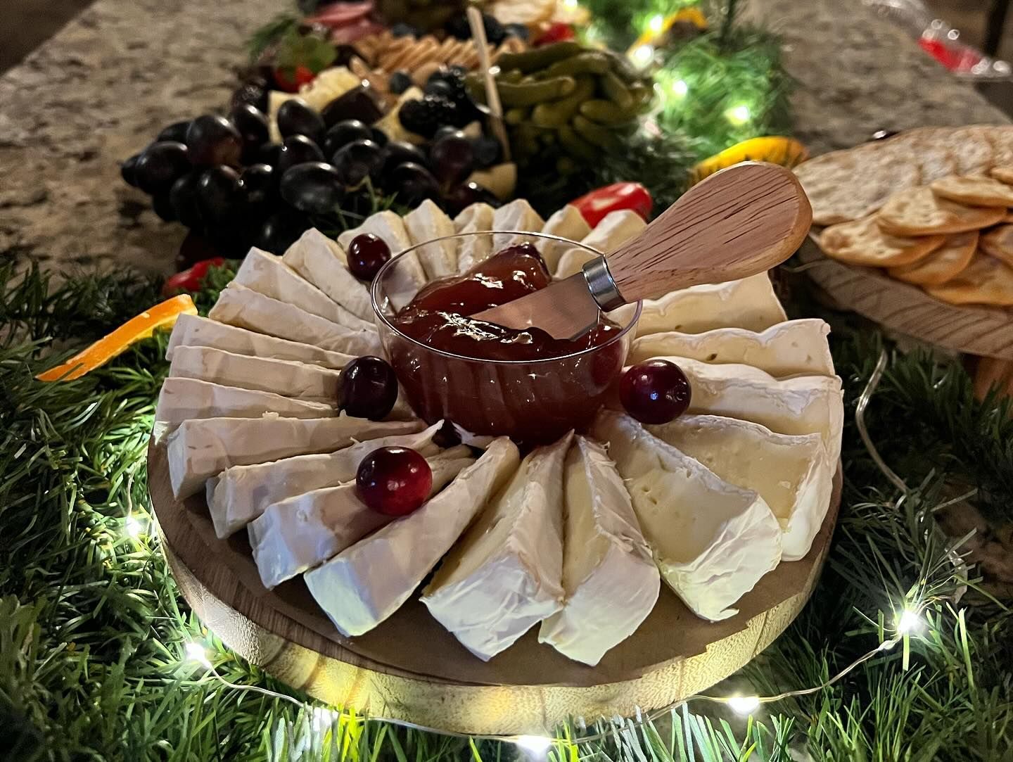 A plate of cheese with cherries on top of it on a table.