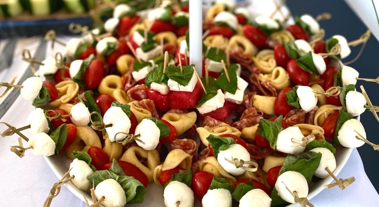 A white plate topped with a variety of food on skewers.