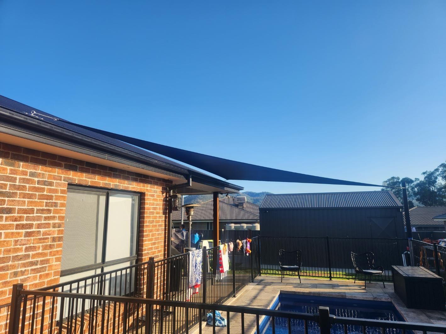 Swimming Pool in The Backyard of A House With Black Shade Sail — New England Shade Sails in Armidale, NSW