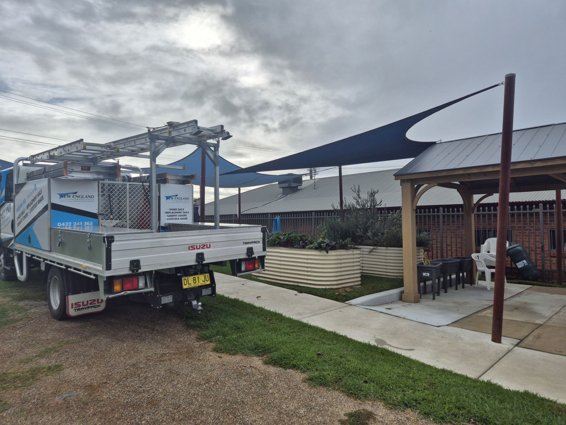 A White Van Is Parked in A Grassy Field Next to A Red Shade Sail — New England Shade Sails in North Tamworth, NSW