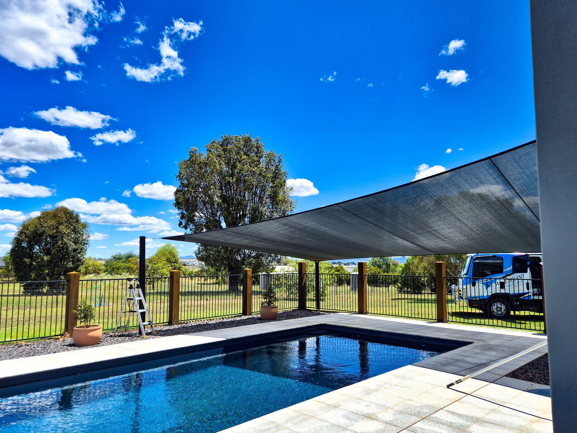 A Group of Umbrellas Are Sitting on Top of A Roof Next to A Pool — New England Shade Sails in North Tamworth, NSW