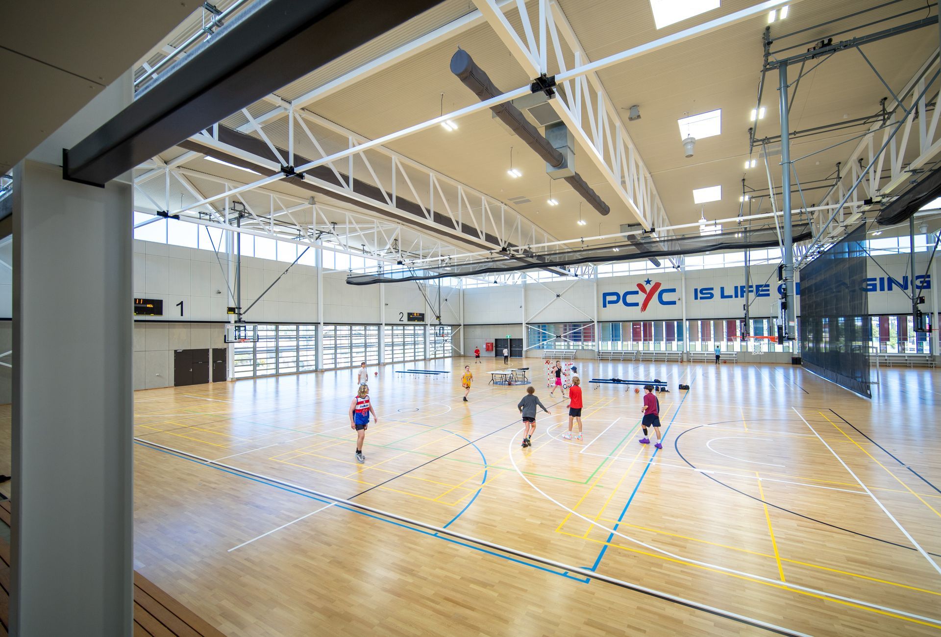 A group of people are playing basketball in a large gym.