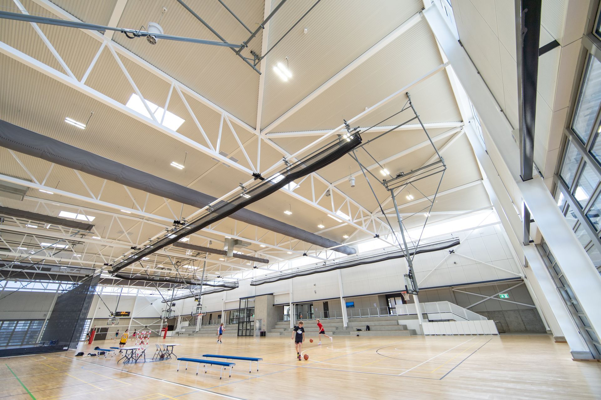 A large indoor gym with a wooden floor and a basketball hoop.