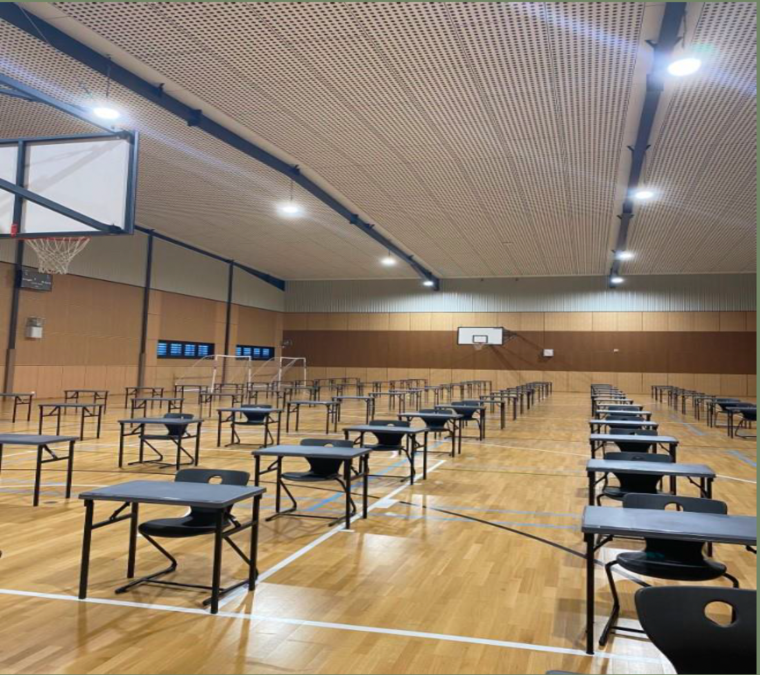 A gym with tables and chairs and a basketball hoop