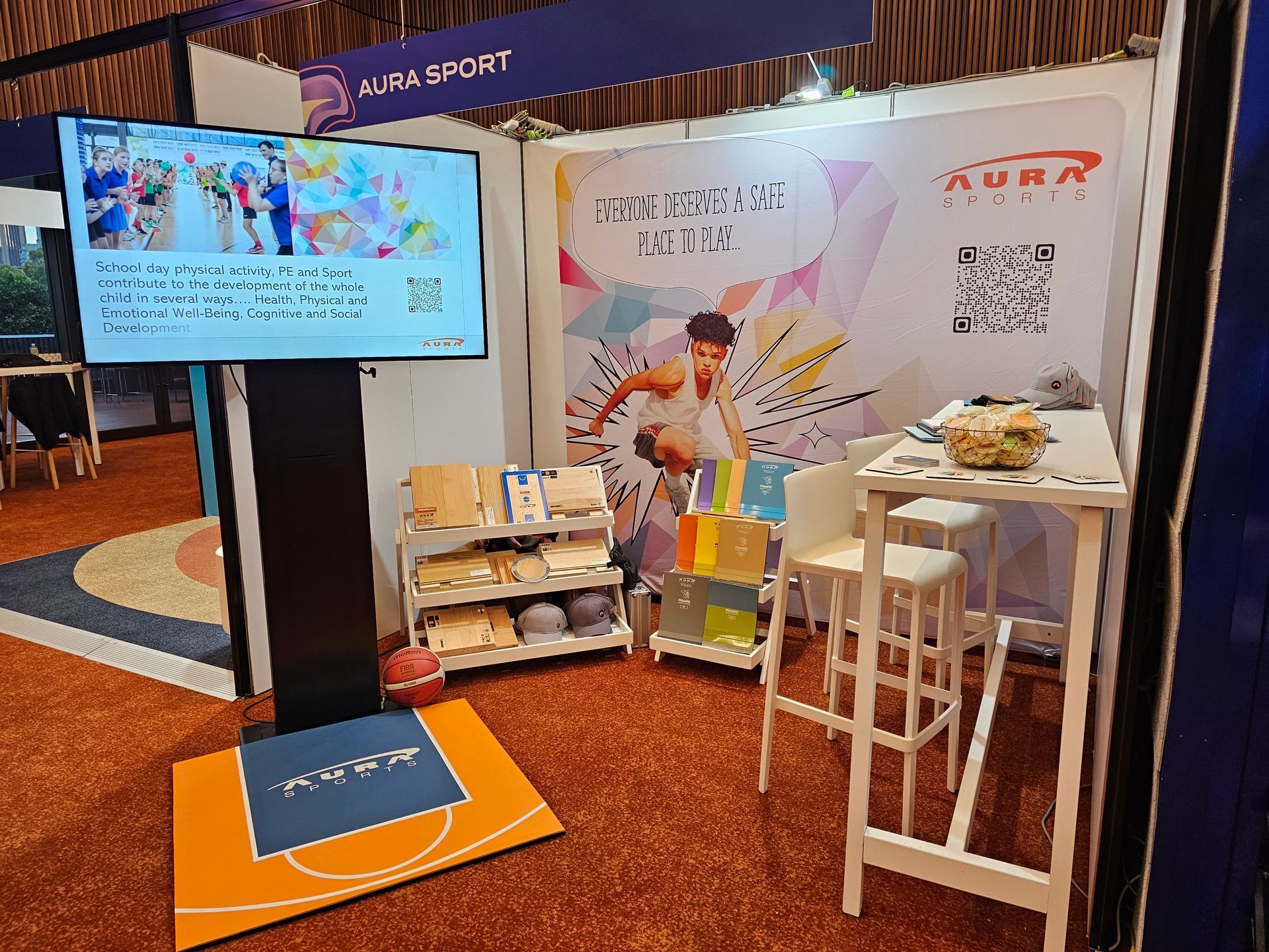 A basketball court is in the middle of a room with tables and chairs.